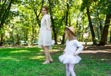 Hasır şapkalı küçük kızıyla yürüyen bir anne..