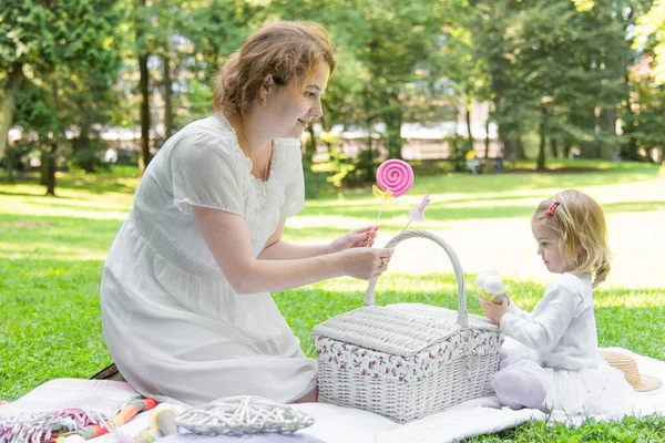 Beautiful little girl in a park on a picnic with straw basket and hat. Spring sunny concept. Happy mothers day. Happy loving family. Mother and daughter.