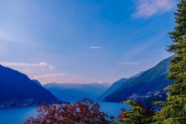 Güneşli bir günde, köknar ağacı ve kırmızı ağacı olan bir dağ gölü manzarası.