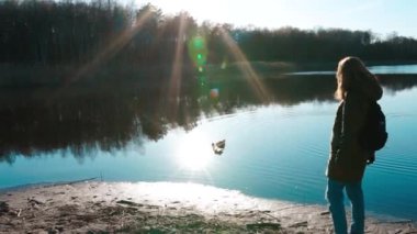 Kız mavi gölün üzerinde güneşin altında duruyor.