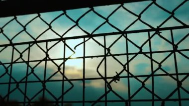 Günbatımı arka planında demir ağ çiti