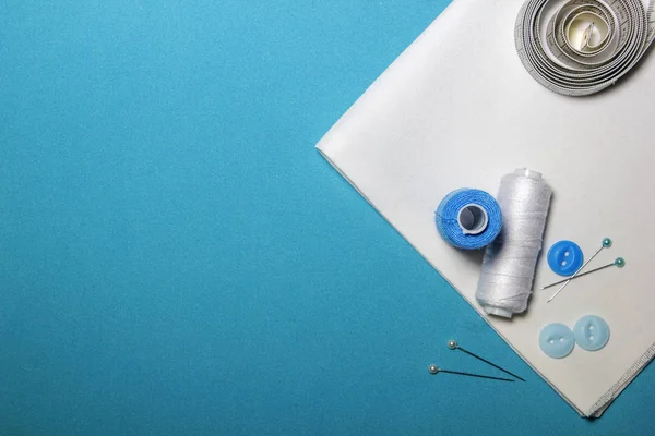 Sewing accessories and fabric on a blue background. Sewing threads, needles, pins, fabric.
