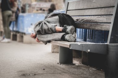 Fakir evsiz bir adam ya da şehirdeki şehir sokaklarında ahşap bankta uyuyan mülteci, sosyal belgesel konsepti, seçici odaklanma