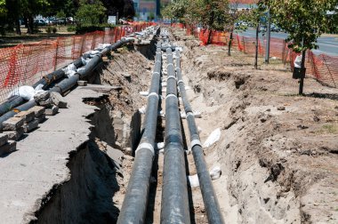 Bölge Isıtma sistemi boru hattı onarım ve yeniden yapılanma paralel borular ile yapı sitesi güvenlik ağı çitleri ile sokak.