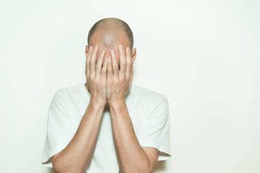 Genç adam acı yüzünü elleri ile akıl hastalığı anksiyete ve duygu mutsuz kapak ve beyaz duvara yaslanmış depresif