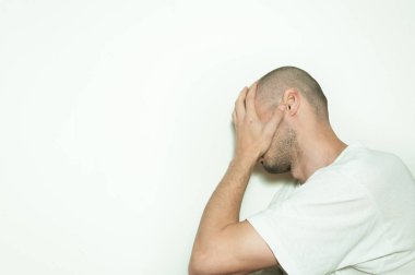 Genç adam acı yüzünü elleri ile akıl hastalığı anksiyete ve duygu mutsuz kapak ve beyaz duvara yaslanmış depresif