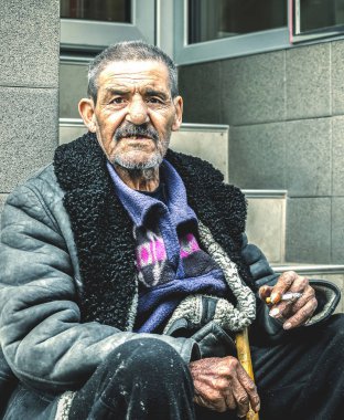 Yoksul ve evsiz çingene ihtiyar sokak duman sigara merdivenlerde oturan ve insanlar, sosyal belgesel kavramı para için yalvarıyor