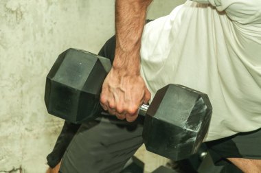 Spor salonunda sırt kasları için egzersiz olarak büyük siyah ağır halter ağırlık tutan güçlü bir kaslı adamın elini