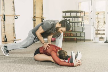 Yakışıklı erkek kişisel antrenör sakallı genç fitness kıza sert eğitim, seçici odak sonra kasları germek için yardım