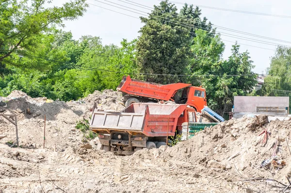 Two industrial tipper trucks on the earth or ground excavation site ready to be loaded