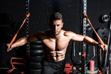 Genç, güçlü, terli, formda, kaslı, formda, göğüs germe egzersizi, dayanıklılık için kauçuk ve iyi görünümlü, koyu renk bir imaj.