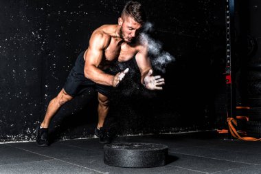 Genç, formda, kaslı, iri kaslı, şınav çeken, antrenman yapan, spor salonundaki halter ağırlık plakasının üstünde hareket bulanıklığıyla elini çırpan bir adam.