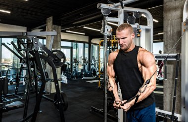 Genç, güçlü, terli, formda kaslı vücut geliştirici göğüs germe egzersizi için spor salonundaki kablo makinesinin üzerinde güç ve iyi görünümlü kas antrenmanı.