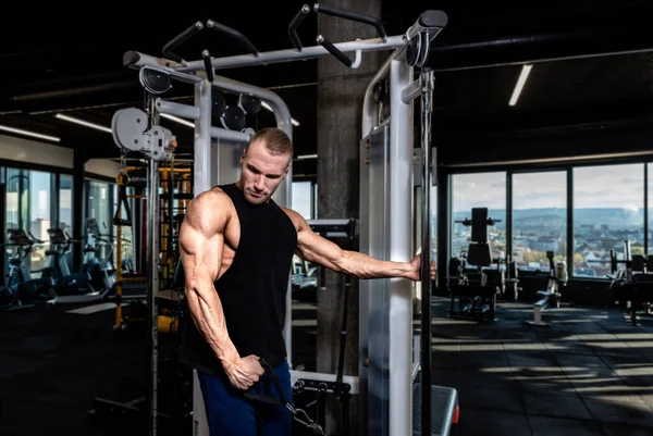 근육질의 남자가 근육을 케이블 기계로 헬스클럽에서 운동을 — 스톡 사진