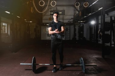 Genç kaslı adam ağır ağırlık kaldırma ya da spor salonunda ağırlık kaldırma antrenmanı için ellerine tebeşir koymaya hazırlanıyor.