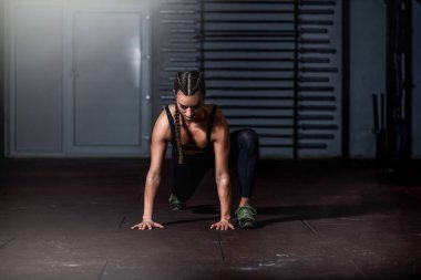 Genç, güzel, kaslı, çekici, formda bir kız spor salonunda vücut ve el kaslarını esnetiyor.