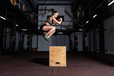 Genç, güçlü, terli, kaslı, iri kaslı bir kız. Spor salonunda vücut geliştirme egzersizi yapıyor. Seçici odak hareketi bulanık.