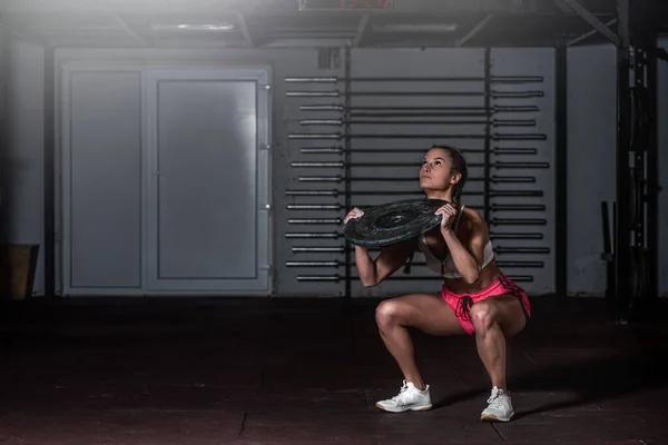 年轻强壮的 汗流浃背的 体格健壮的 肌肉粗壮的女孩子 在健身房的地板上 用杠铃式负重板做腿部 肩部肌肉或腹肌等强韧的交叉训练 — 图库照片