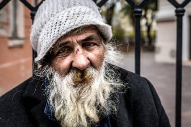 Sokakta dolaşan beyaz sakallı, yaşlı, alkolik adamın portresi. Hasta ve yalnız, sosyal konular belgesel konsepti.