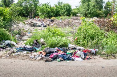 Eski giysi ve ayakkabı yığını çimenlere çöp ve çöp olarak atılır, çevreyi kirletir ve kirletir.