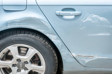 Kazadan ve çarpışmadan sonra tekerlek ve kapıların yanında çizik ve hasar görmüş yeni gümüş renkli Audi arabası.