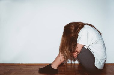 Yalnız, üzgün ve depresif bir kız çocukken tacize uğramış odasında yerde tek başına oturmuş ve korku içinde ağlıyor.