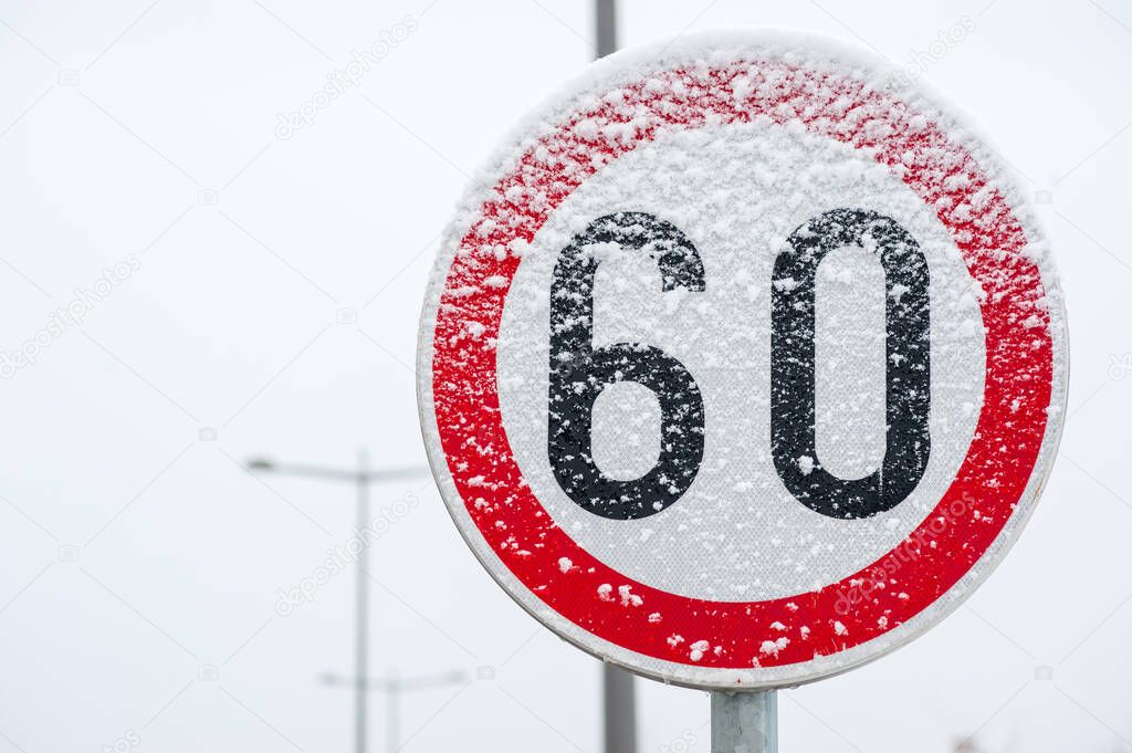 Traffic road speed limit 60 sign on the street covered with snow in danger slippery winter season close up