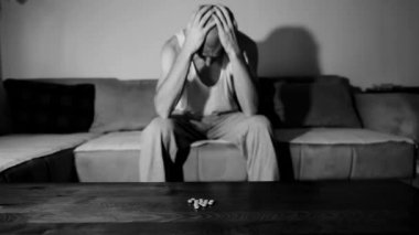 Depresyonda olan depresyonlu bir adam aşırı dozda ilaç ve ağrı kesiciler alarak intihar etmek ister. Karanlık odasında otururken seçici, karamsar, dramatik bir görünüm sergiler.