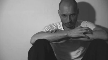 Yalnız ve bunalımlı bağımlı bir adam karanlık evinde yerde tek başına oturuyor. Sefil ve kaygılı karanlık görüntüler çekiyor. Sosyal sağlık hizmetleri kavramı siyah ve beyaz.