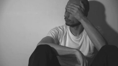 Yalnız ve bunalımlı bağımlı bir adam karanlık evinde yerde tek başına oturuyor. Sefil ve kaygılı karanlık görüntüler çekiyor. Sosyal sağlık hizmetleri kavramı siyah ve beyaz.