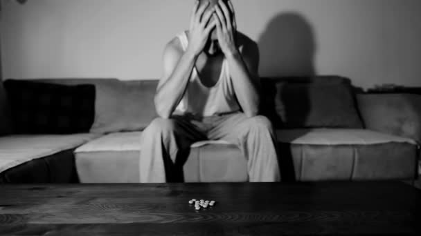 自殺うつ病に苦しんでいるうつ病男は 過剰摂取によって自殺したい強い薬や薬を服用痛みキラー彼の暗い部屋に座って選択的なフォーカスムーディー劇的な外観 — ストック動画
