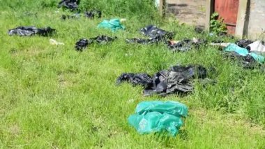Yeşil çimenlerin üzerindeki siyah plastik çöp torbaları parktaki çöp ve çöplerle çevreyi ve doğayı kirletiyor.