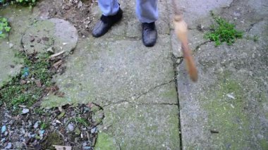 Süpürge süpüren ve kirli arka bahçesini süpürgeyle temizleyen adam çöpleri ve yaprakları temizliyor. 