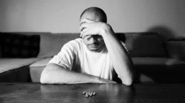 Depresyonda olan depresyonlu bir adam aşırı dozda ilaç ve ağrı kesiciler alarak intihar etmek ister. Karanlık odasında otururken seçici, karamsar, dramatik bir görünüm sergiler.