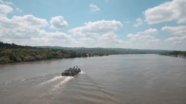 Sırbistan 'ın Novi Sad kenti yakınlarındaki Tuna Nehri' nde Fruska gora dağı ve mavi gökyüzü ile sanayi gemisi veya gemi seyrediyor