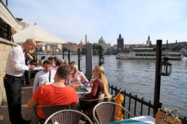 People in outdoor cafe on the Vltava river waterfront in Prague — Stock Photo, Image