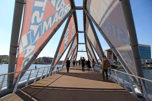 Nemo museum Amsterdam yakınındaki modern köprü üzerinde yürüyen insanlar — Stok fotoğraf