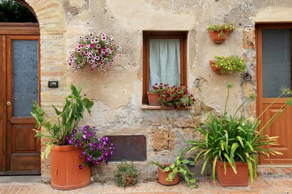 Gammelt hus dekorert med blomsterpotter i Toscana, Italia – stockfoto