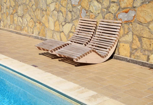 Camas de sol de madeira ao ar livre no resort terraço junto à piscina — Fotografia de Stock