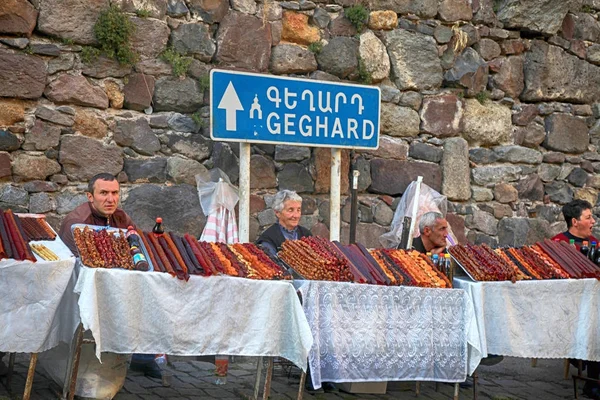 La gente local vende dulces caseros armenios cerca del antiguo templo de Geghard, Armenia . — Foto de Stock