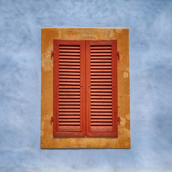 Geschlossenes Fenster mit braunen Rollläden an blauer alter Wand — Stockfoto