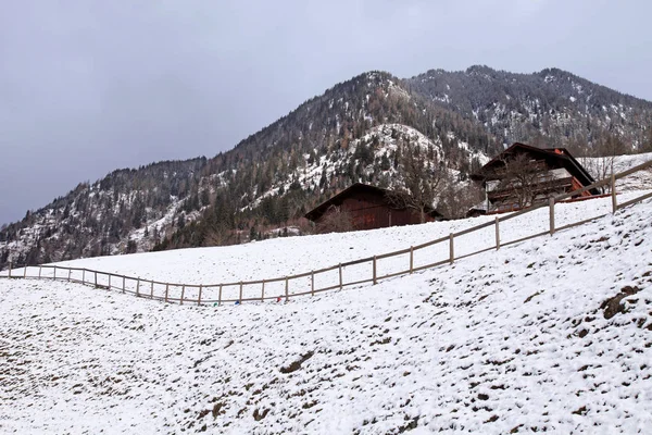 Pejzaż zimowy z drewnianych chatach i góry w alpejskiej wiosce — Zdjęcie stockowe