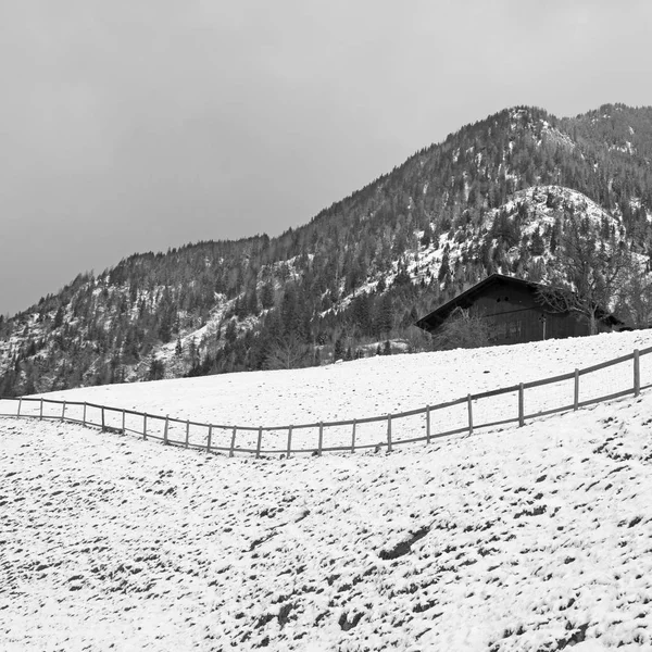 Zimowy krajobraz z drewnianymi chatkami i górą w małej alpejskiej wiosce — Zdjęcie stockowe