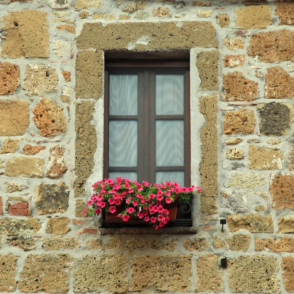 Italienisches Fenster mit schönen Blumen in altem Steinhaus, Toskana, Italien — Stockfoto