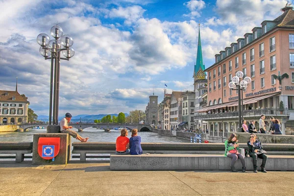 Persone sedute e rilassanti sul ponte del fiume Limmat, Zurigo, Svizzera . — Foto Stock