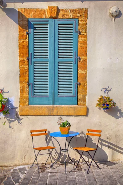 Persianas azules ventana y hermosas sillas pequeñas y una mesa, Chipre — Foto de Stock