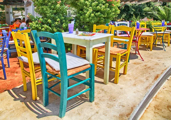 De Griekse taverne stoep met veelkleurige tafels en stoelen, Crete — Stockfoto