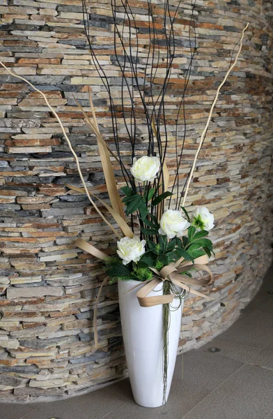 Beautiful white vase with flowers on the floor in the hall.