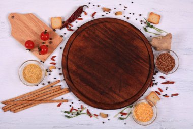 Kahverengi yuvarlak kesme tahtası üzerinde beyaz ahşap masa etrafında gıda çerçeve