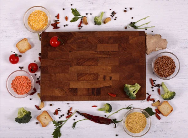Voedsel frame rond lege bruin snijplank op witte houten tafel — Stockfoto